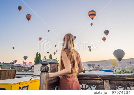 Tourist woman looking at hot air balloons in Cappadocia, Turkey. Happy Travel in Turkey concept. Woman on a mountain top enjoying wonderful view 97074184