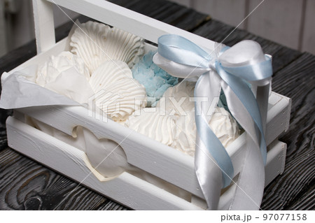 Marshmallow cones. Homemade zephyr. Packed in a wooden decorative box. On the background of the boards. Close-up. 97077158