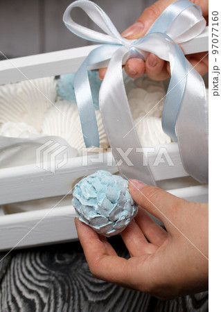 Marshmallow cones. Homemade zeohyr. The woman puts it in a wooden decorative box. On the background of the boards. Close-up. 97077160
