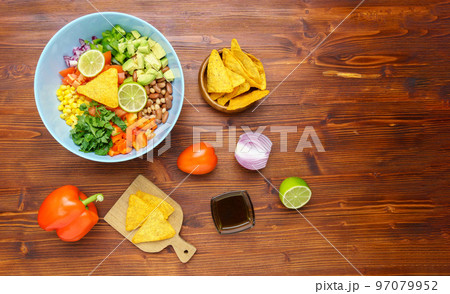 Mexican vegetable salad, cowboy caviar in bowl with ingredients and nachos. Top view. Copy space 97079952