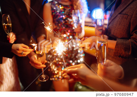 Sparkling sparklers in the hands. Playing firework to celebrate winter holidays with friends at party. 97080947
