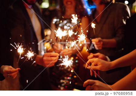 Sparkling sparklers in the hands. Playing firework to celebrate winter holidays with friends at party. 97080958