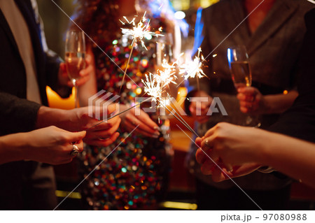 Glowing sparkles in hands. Group of happy people enjoying party with fireworks. Winter holiday. Glowing sparkles in hands. Group of happy people enjoying party with fireworks. Winter holiday. 97080988