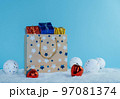 A paper bag filled with gifts stands in the snow. Christmas decorations. 97081374