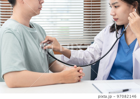Female doctor physician is examines heart and lungs of male patient with a stethoscope to check Female doctor physician is examines heart and lungs of male patient with a stethoscope to check 97082146
