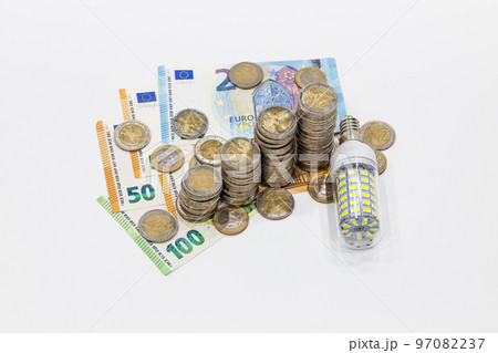Stacked coins on Euro banknotes and light bulb. Concept of expensive electricity costs Stacked coins on Euro banknotes and light bulb. Concept of expensive electricity costs 97082237