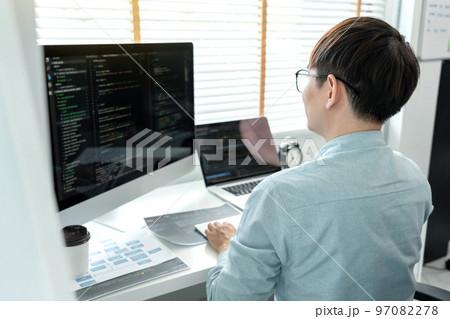 Male programmer is programming to develop program app and website of corporate while working to checking program code and debugging on multiple screen at modern software office Male programmer is programming to develop program app and website of corporate while working to checking program code and debugging on multiple screen at modern software office 97082278
