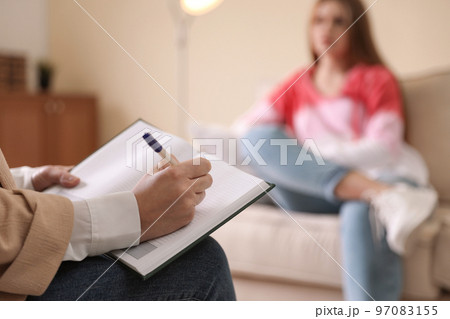 Professional psychotherapist and patient in office, focus on hands with notebook 97083155
