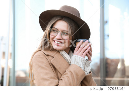 Young woman with cup of coffee on city street in morning 97083164