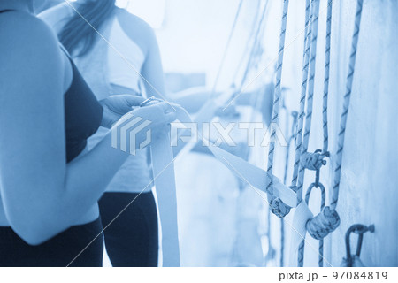Woman holding ropes hanging on yoga studio wall 97084819