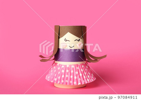 Toy doll made of toilet paper hub on pink background 97084911