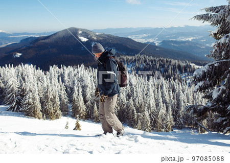 Man with backpack trekking in mountains. Cold weather, snow on hills. Winter hiking. Man with backpack trekking in mountains. Cold weather, snow on hills. Winter hiking. 97085088