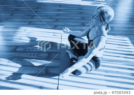 Young woman meditating sitting in lotus position against sunny window 97085093