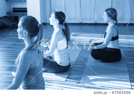 young women in yoga class sitting and relaxing making meditation lotus pose 97085096
