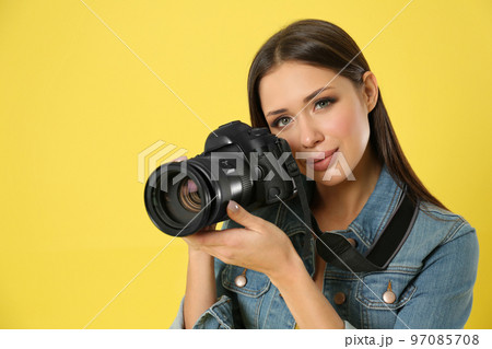 Professional photographer working on yellow background in studio Professional photographer working on yellow background in studio 97085708