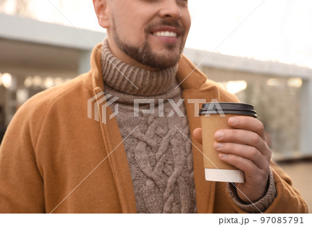 Man with cup of coffee on city street in morning, closeup Man with cup of coffee on city street in morning, closeup 97085791