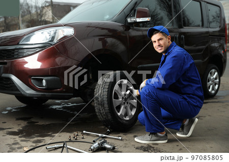 Worker changing car wheel at tire service Worker changing car wheel at tire service 97085805