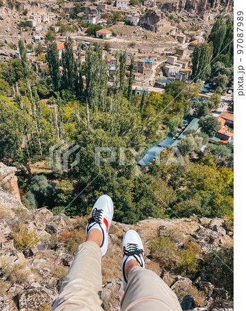 Tourist man outdoor on edge of cliff. Closeup legs over the abyss 97087989