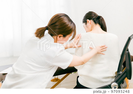 腰痛・脊椎の痛みで整体院・整骨院で施術を受けるアジア人女性医師・理学療法士・看護師と患者 97093248