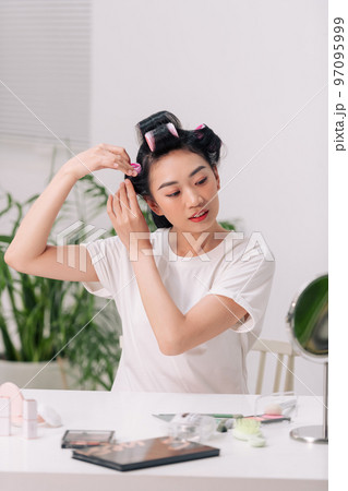 Young woman using hair curlers 97095999