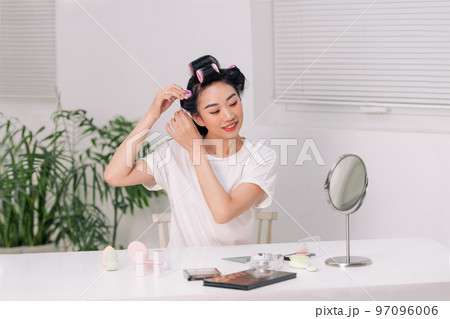 Young woman using hair curlers 97096006