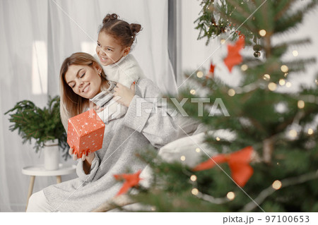 People reparing for Christmas. Mother playing with her daughter. Family is resting in a festive room. Child in a sweater sweater. People reparing for Christmas. Mother playing with her daughter. Family is resting in a festive room. Child in a sweater sweater. 97100653