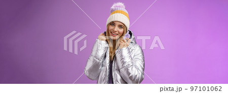 Tender feminine gentle blond girlfriend posing boyfriend take pictures ski resort holiday wearing glittering stylish jacket winter hat standing pleased purple background smiling delighted Tender feminine gentle blond girlfriend posing boyfriend take pictures ski resort holiday wearing glittering stylish jacket winter hat standing pleased purple background smiling delighted 97101062