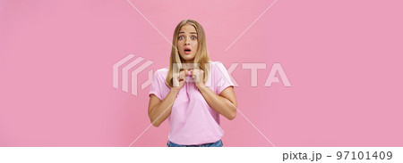 Woman gasping from fright being scared by someone pressing clenched hands to chest bending backwards looking worried and terrified at camera being shocked with unexpected bang over pink wall Woman gasping from fright being scared by someone pressing clenched hands to chest bending backwards looking worried and terrified at camera being shocked with unexpected bang over pink wall 97101409