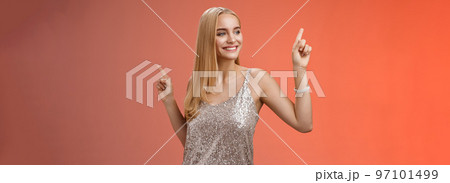 Carefree good-looking stylish glamour blond young 20s woman in silver glittering dress dancing having fun amused go wild party night prom shaking body raising index fingers up, red background Carefree good-looking stylish glamour blond young 20s woman in silver glittering dress dancing having fun amused go wild party night prom shaking body raising index fingers up, red background 97101499