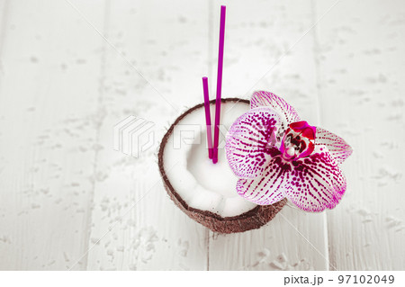 Top down view of fresh coconut with straw which decorated with orchid on wooden white table. Tropic Top down view of fresh coconut with straw which decorated with orchid on wooden white table. Tropic 97102049