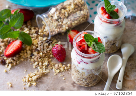 Homemade summer healthy breakfast. Greek yogurt with granola, pieces fresh strawberry on stone table. 97102854