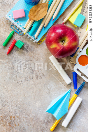 Back to school concept.  School supplies, apple and origami plane on a light stone or slate background. Copy space. 97102868