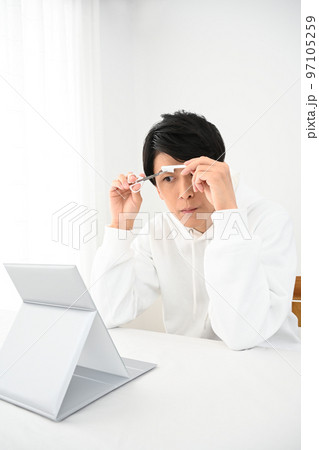 自分で眉毛を整える若い男性 自分で眉毛を整える若い男性 97105259