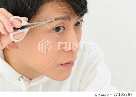 自分で眉毛を整える若い男性 97105267