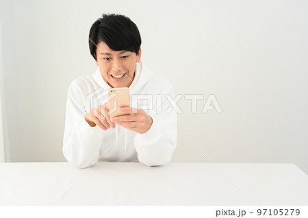 机でスマホを操作する若い男性 机でスマホを操作する若い男性 97105279
