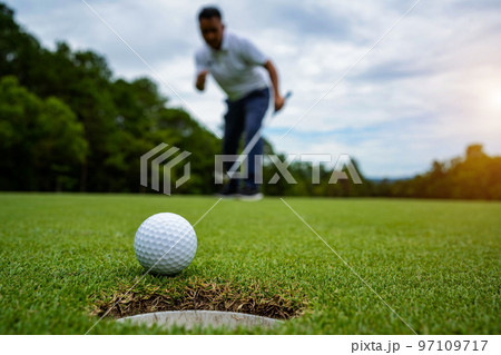 Golfer putting ball on the green golf, lens flare on sun set evening time. Golfer putting ball on the green golf, lens flare on sun set evening time. 97109717
