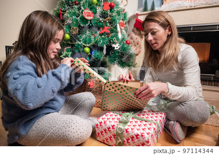 young mother and daughter open Christmas Present Gift Box in front of Xmas Tree. Happy Mom with kid 97114344