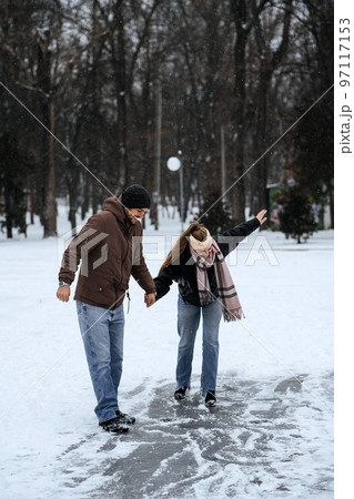 Winter couple activities. Winter Date Ideas to Cozy Up. Cold season dates for couples. Young couple in love waking, skating and having fun in winter snowy park. 97117153