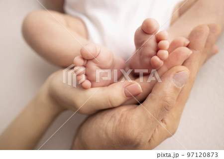 Children's foot in the hands of mother, father, parents. Feet of a tiny newborn close up. Little baby legs. Mom and her child. Happy family concept. Beautiful concept image of motherhood stock photo.  97120873