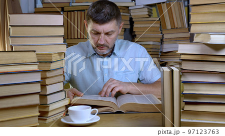 A bearded man reads a book in the library A bearded man reads a book in the library 97123763
