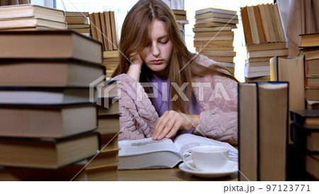 A girl reads a book in the library A girl reads a book in the library 97123771