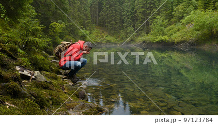 Bearded man with a backpack near a beautiful mountain lake Bearded man with a backpack near a beautiful mountain lake 97123784
