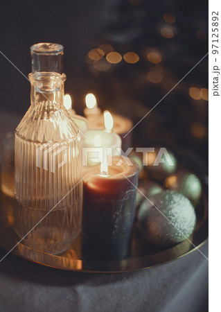 New Year's still life. Glasses and a decanter from transparent glass, candles and golden xmas ball New Year's still life. Glasses and a decanter from transparent glass, candles and golden xmas ball 97125892