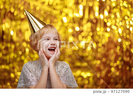 A child in a festive hat and a shiny dress. A child in a festive hat and a shiny dress. 97127090