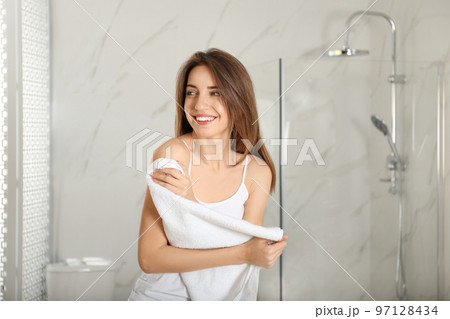 Young woman wiping body with towel indoors 97128434