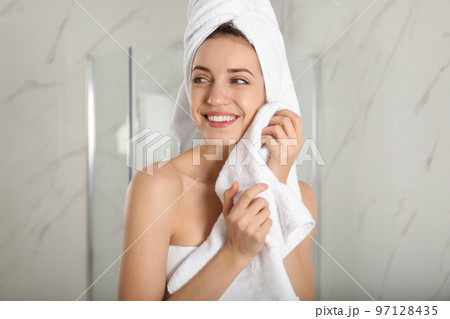 Young woman wiping face with towel in bathroom 97128435