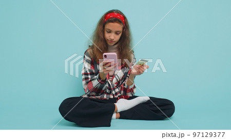 Child girl using credit bank card and smartphone while transferring money, purchases online shopping Child girl using credit bank card and smartphone while transferring money, purchases online shopping 97129377