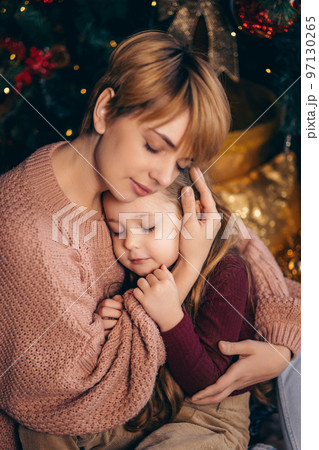 Mom and daughter in a decorated Christmas living room at home Mom and daughter in a decorated Christmas living room at home 97130265
