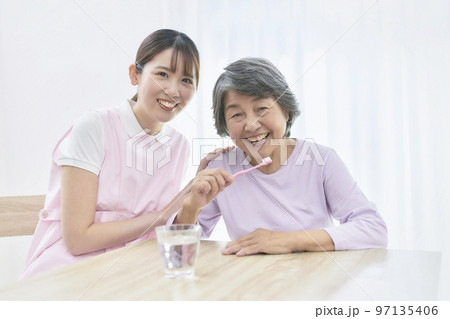 シニア女性の歯磨き指導をする若い歯科衛生士 97135406