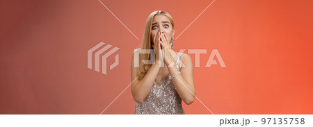 Shocked afraid insecure terrified unconfident concerned young blond woman in silver stylish dress gasping horrified pop eyes stunned red background look afraid, panicking witness crime Shocked afraid insecure terrified unconfident concerned young blond woman in silver stylish dress gasping horrified pop eyes stunned red background look afraid, panicking witness crime 97135758